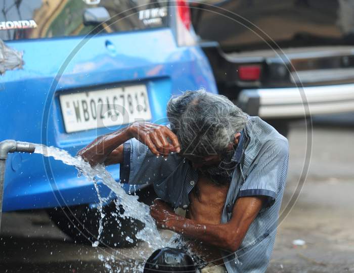 Indian old man taking a bath at the water tap