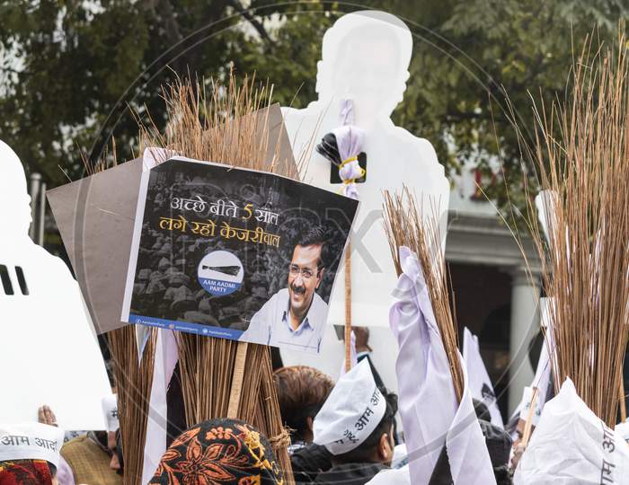 Aam Aadmi Party AAP supporter holding cutout of Arvind Kejriwal, flags and AAP electoral symbol Broom during a rally for Delhi Assembly Election