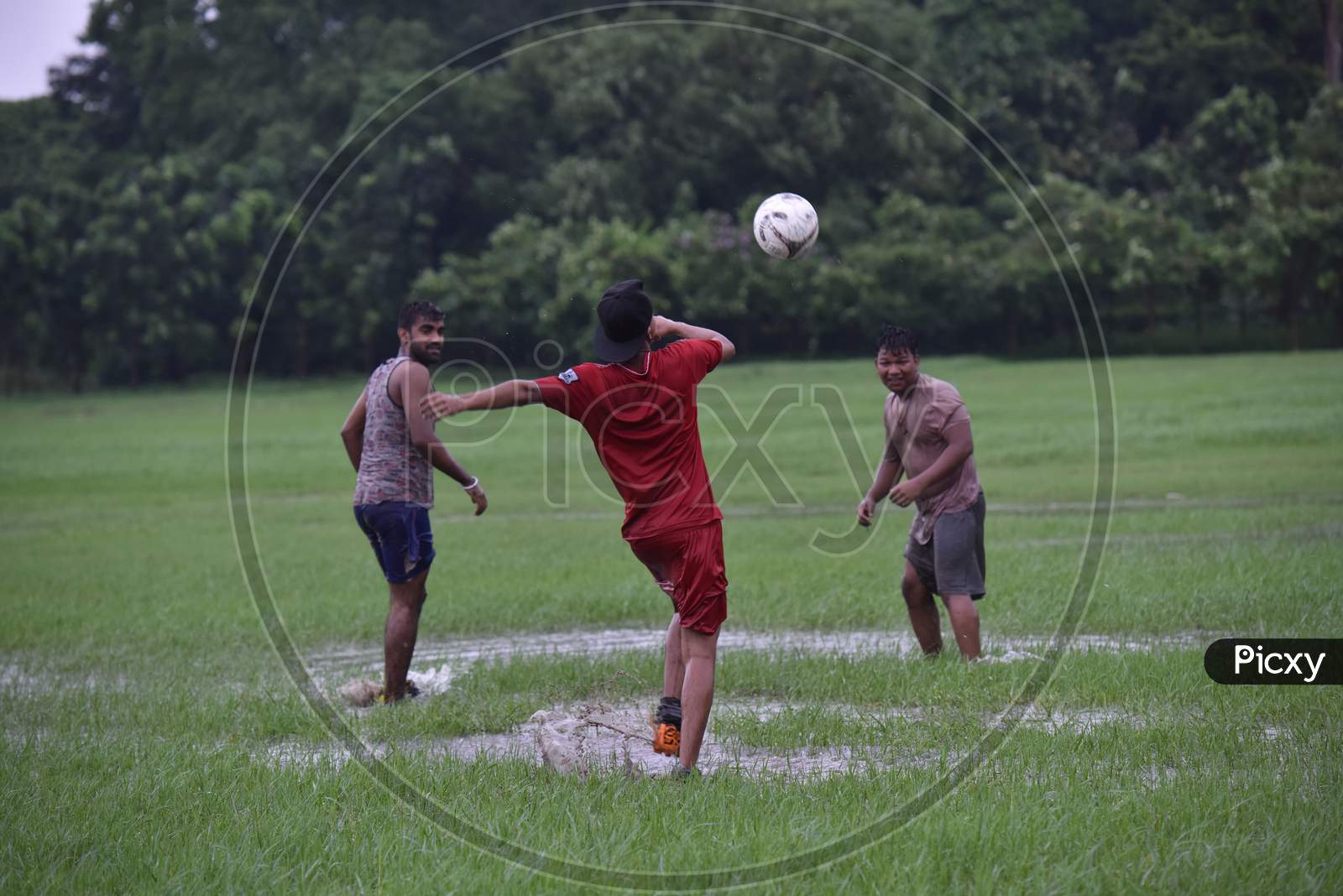 Indian boy attempting a free kick during rain
