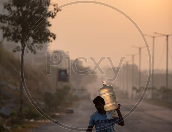 A Man Carrying Water Can On His Shoulder  on Kaithalapur Road On an Winter Morning