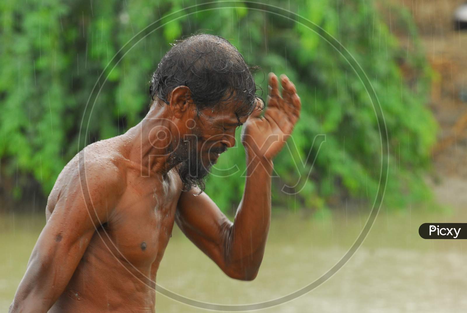 Indian bare chested man wiping water from his face
