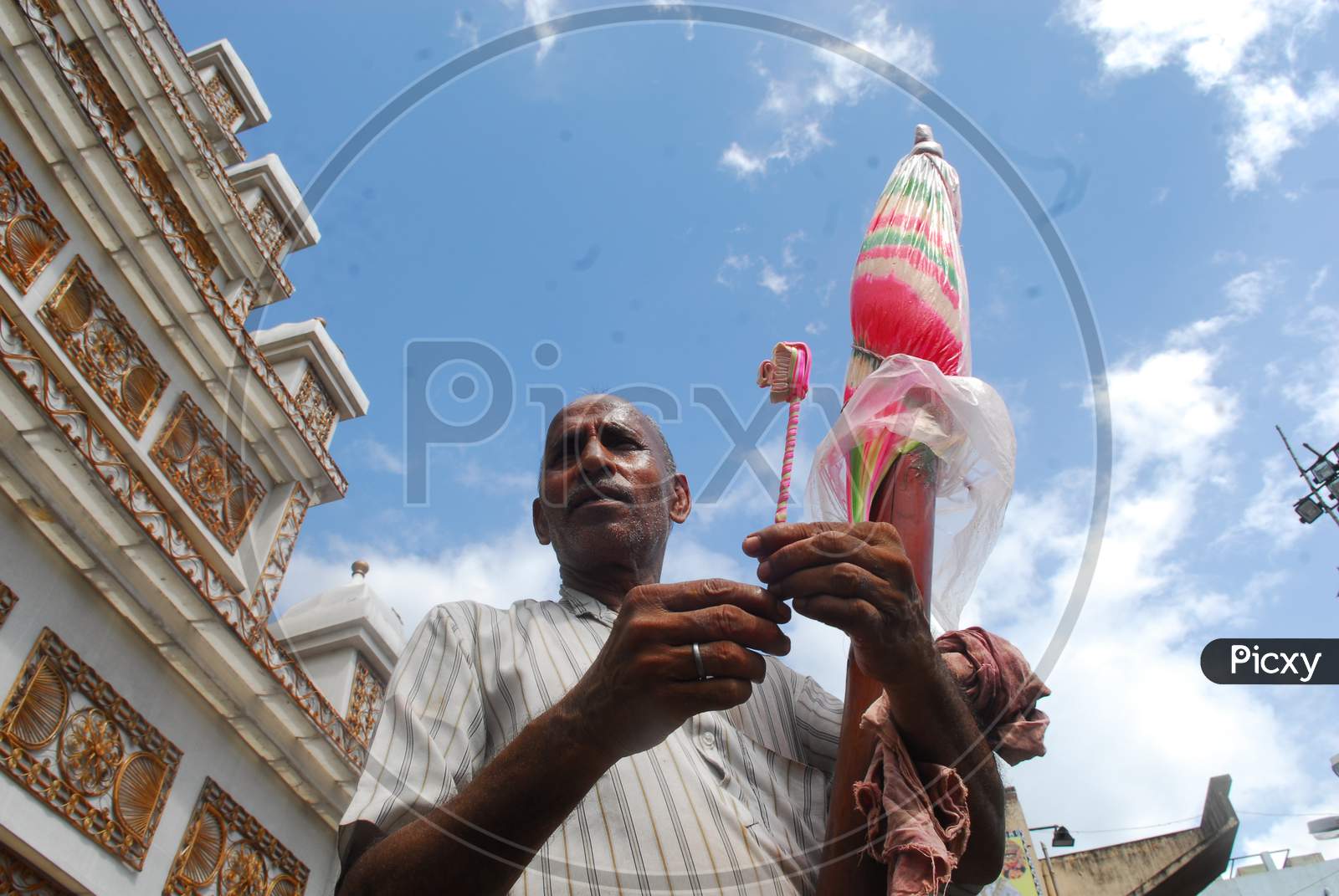 Indian Man making a toothbrush with candy
