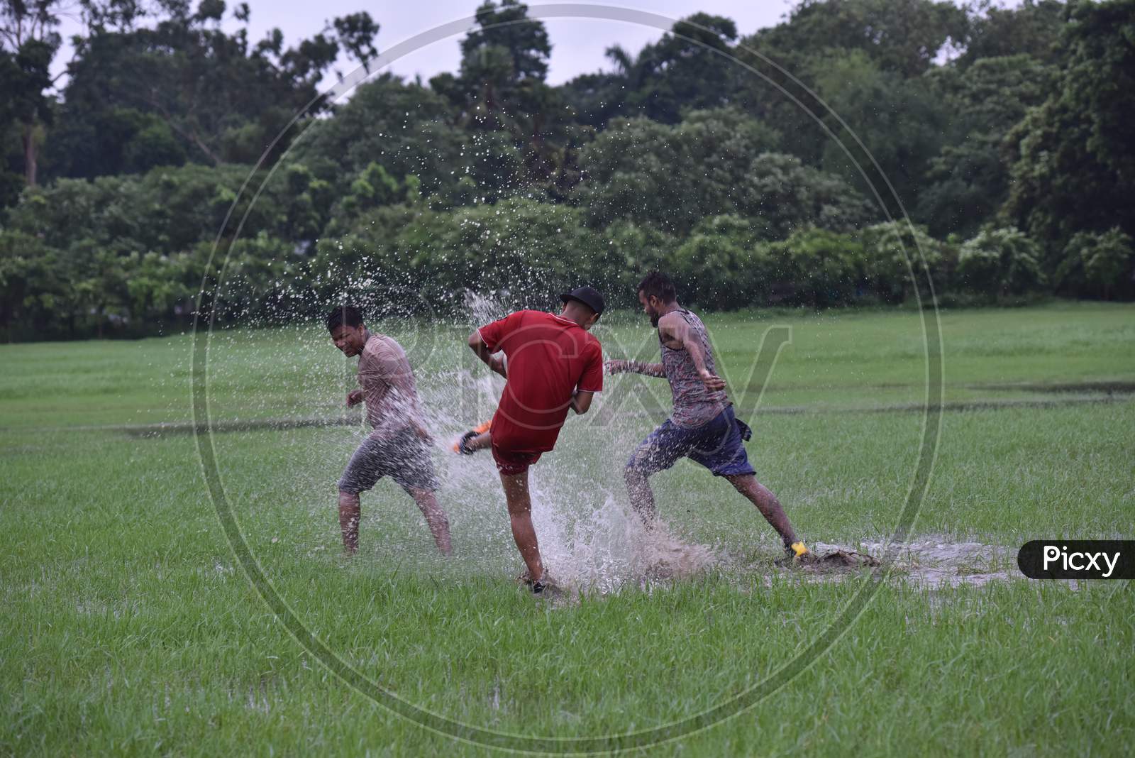 Indian boys playing with football in the rain