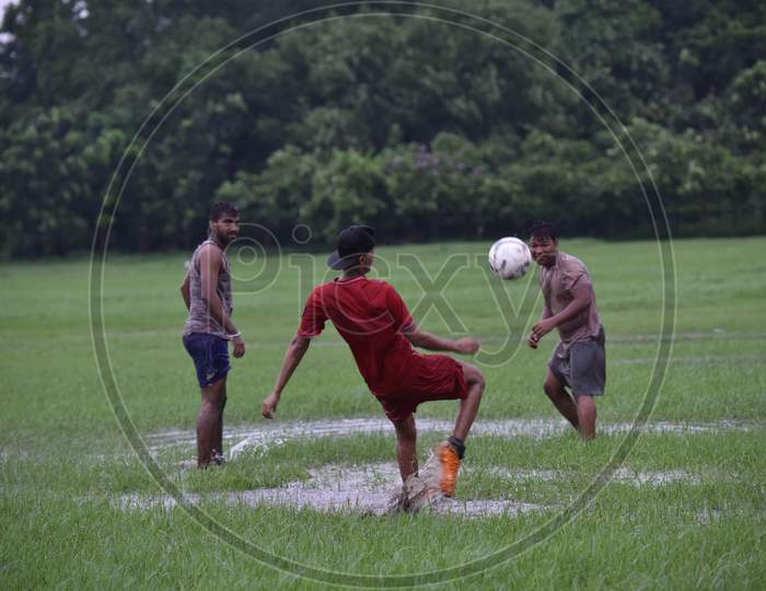Indian boy attempting a football kick during rain