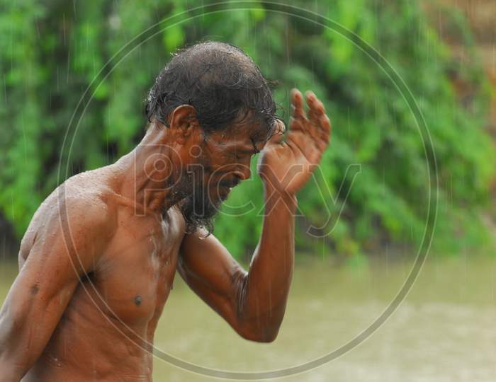 Indian bare chested man wiping water from his face