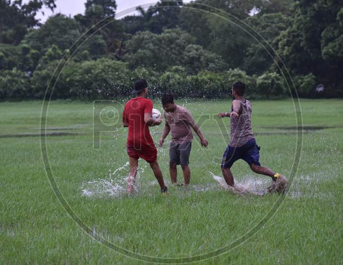 Indian boys playing football in the lawn during rain