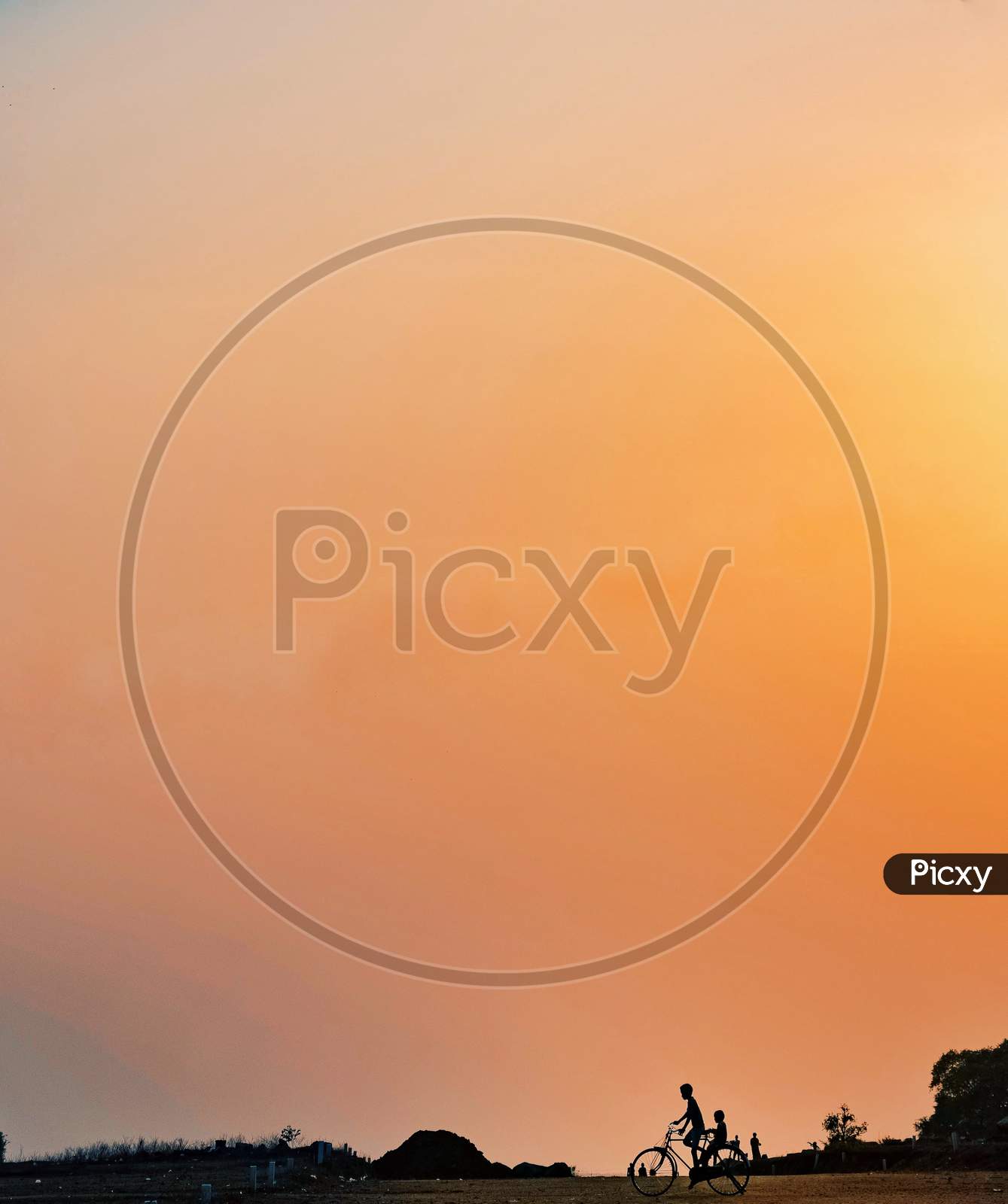 Silhouette Of Children Riding Bicycle With Sunset Sky in Background