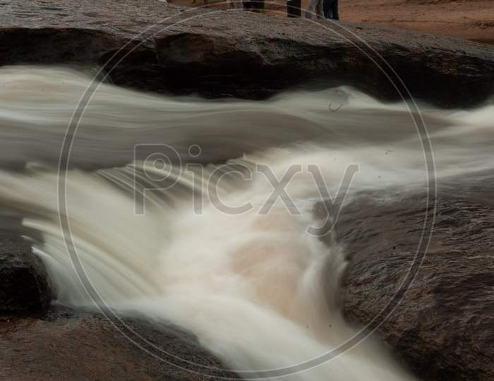 Smooth Silky Texture Of Water Flowing Over  Stones At an Water Channel In Forest