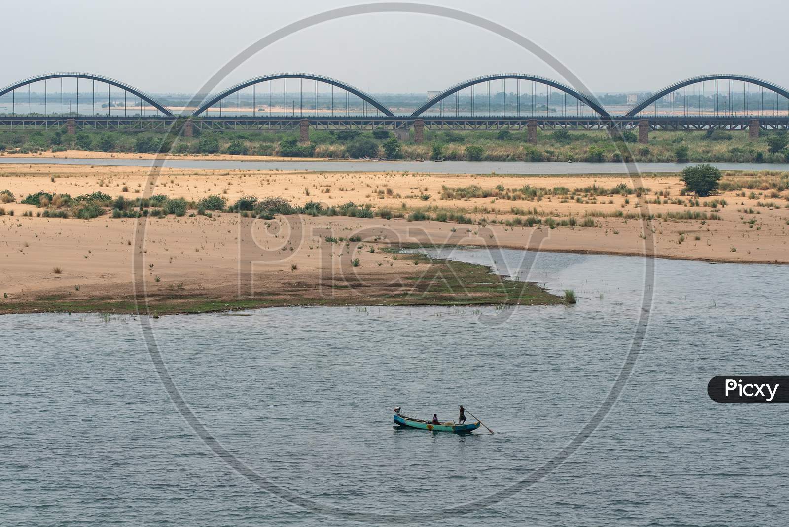 A fishing boat in godavari river with a view of Godavari Railway Arch bridge
