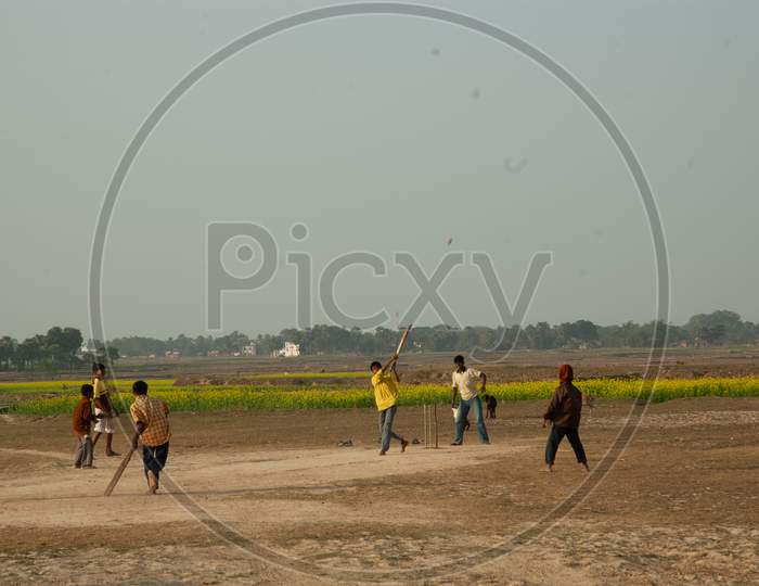 Indian Young Man Playing Cricket At Fields in Indian Rural Villages