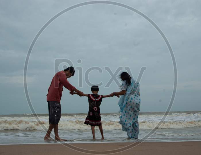 Indian father and mother with their daughter by the beach