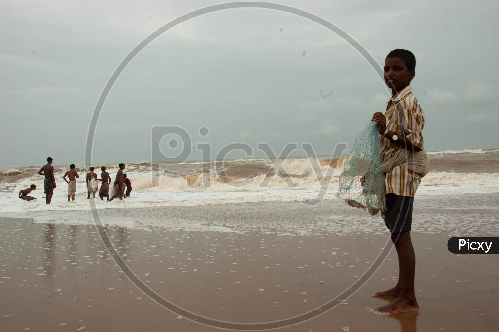 Indian fisher-boy holding fish in the cast net