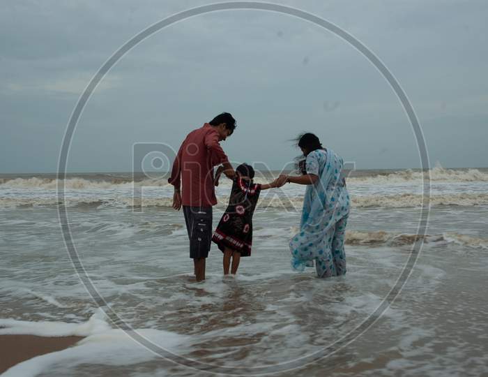 Indian Father and Mother lifting her child by the beach