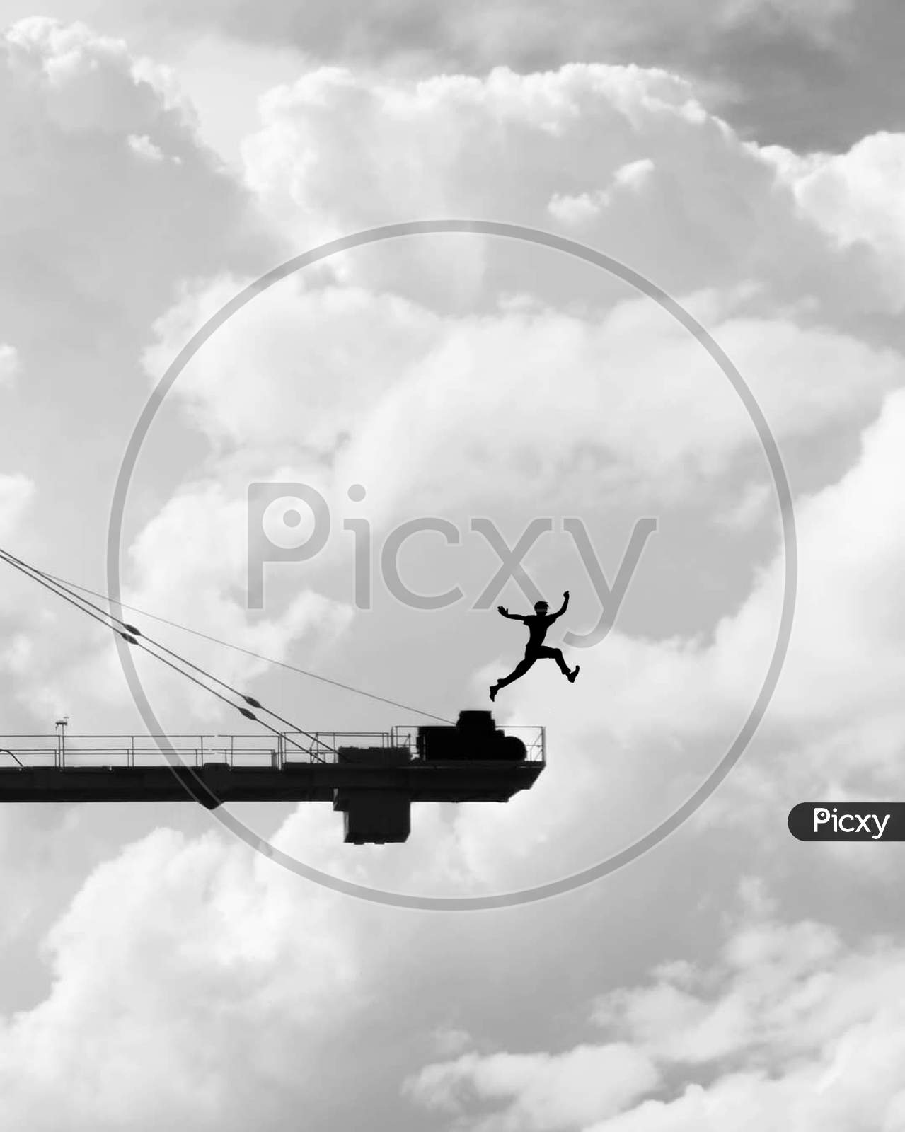 Silhouette of an Man Jumping From an Construction Crane With Clouds In Background
