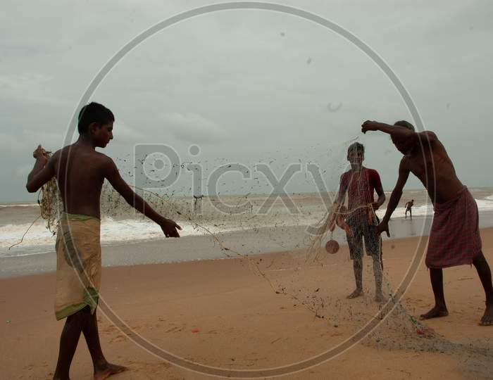 Indian fishermen rolling the fishing net by the beach