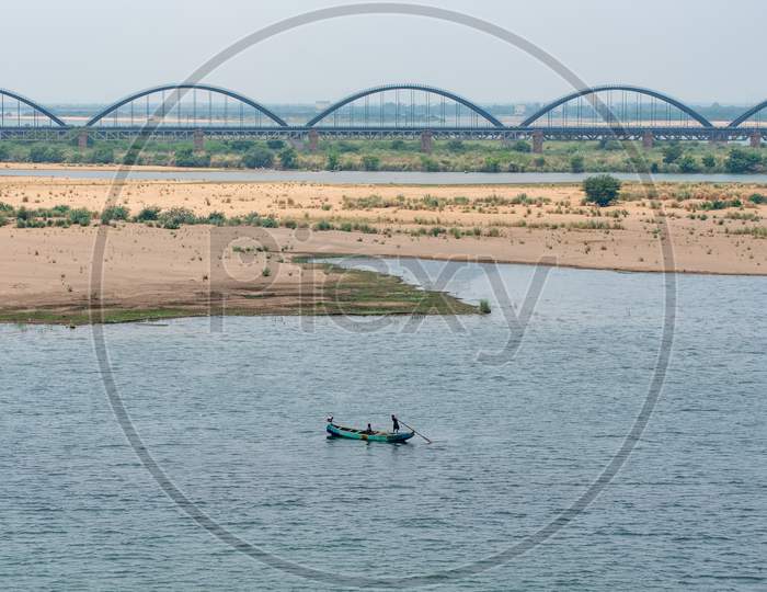 A fishing boat in godavari river with a view of Godavari Railway Arch bridge