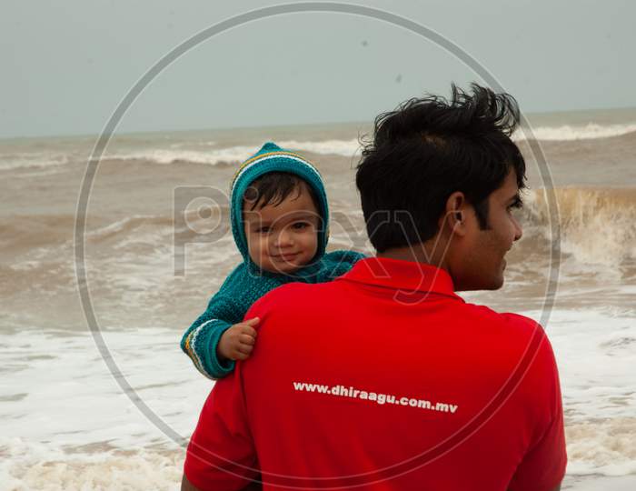 Indian father holding his baby by the beach