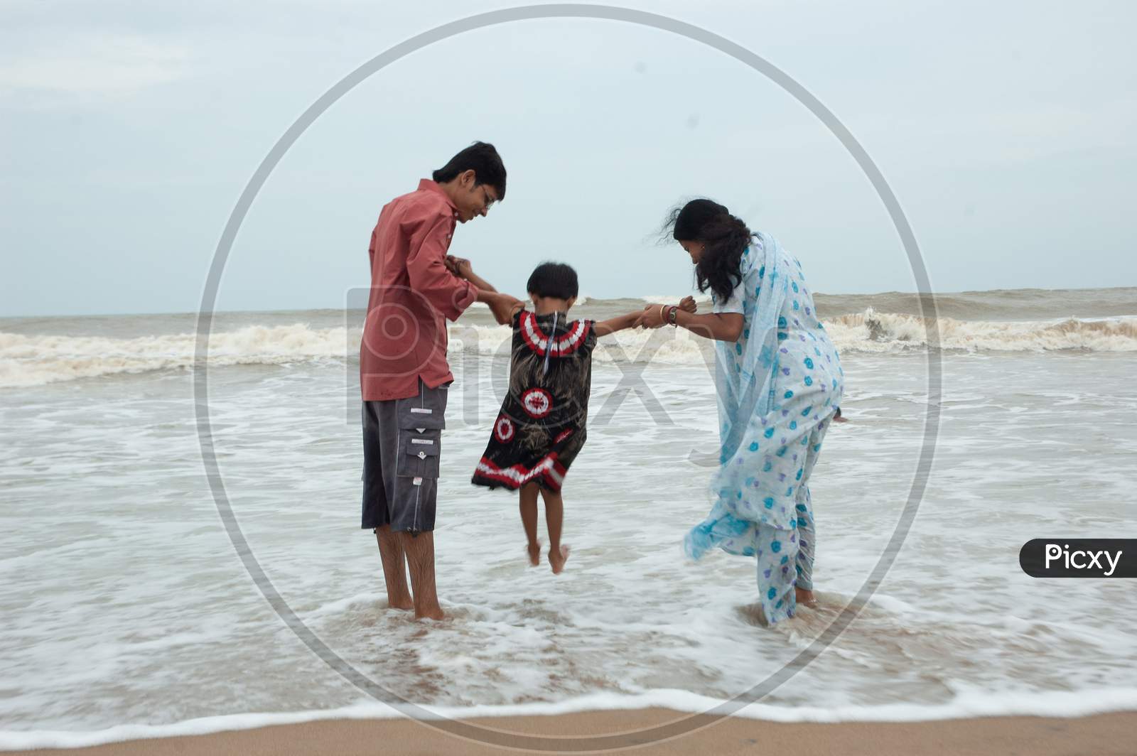 Indian Parents helping her kid touch the waves