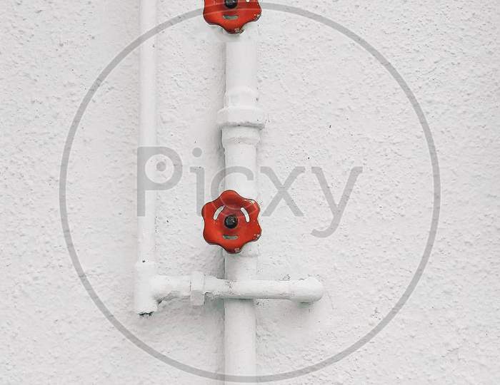 A Water Pipe With Valve  Over White Painted  Walls
