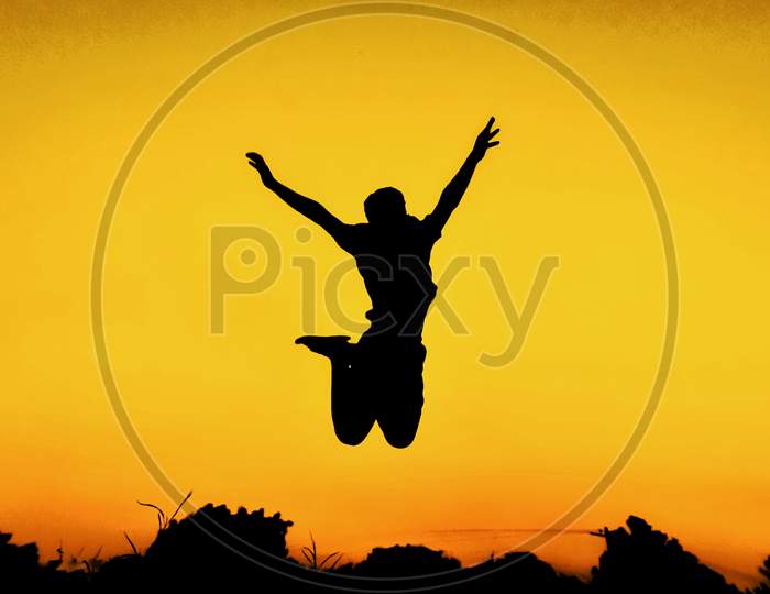 Silhouette Of Man Jumping In Joy  Over Golden Sky Background