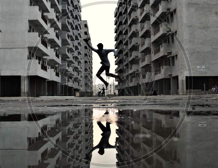 Silhouette Of Man Jumping in Joy With Apartments in Background