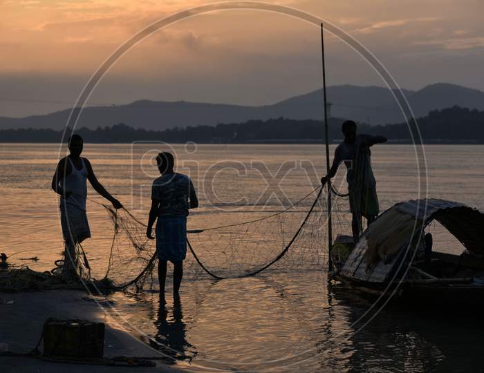 Fishermen Cleaning Their Fishing Nets After Fish In The Brahmaputra River, In Guwahati, Assam