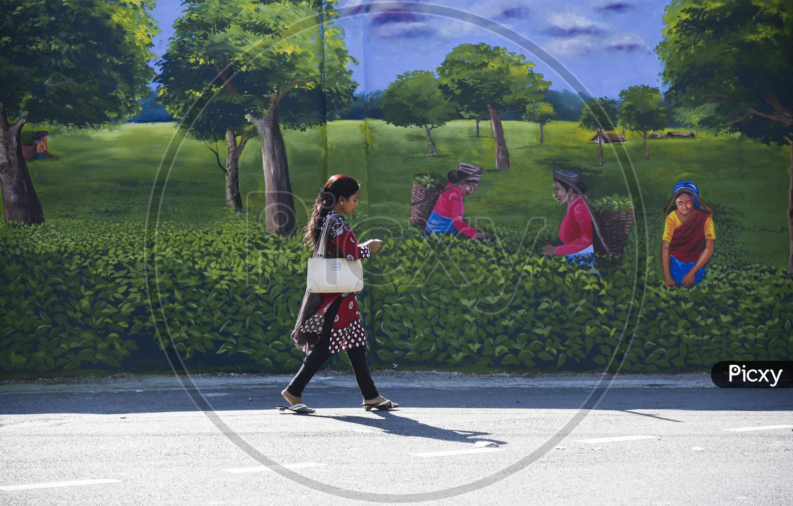 People Walking In Front Of A Mural