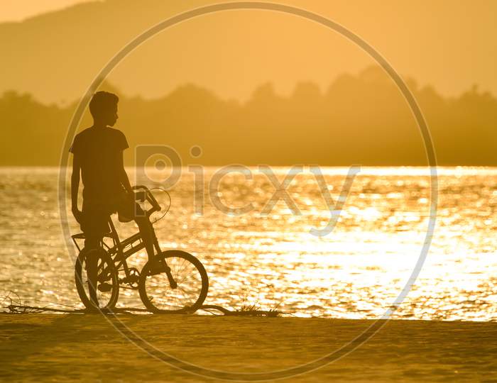 Silhouette of A Boy On Bicycle At Bramhaputra River Bank