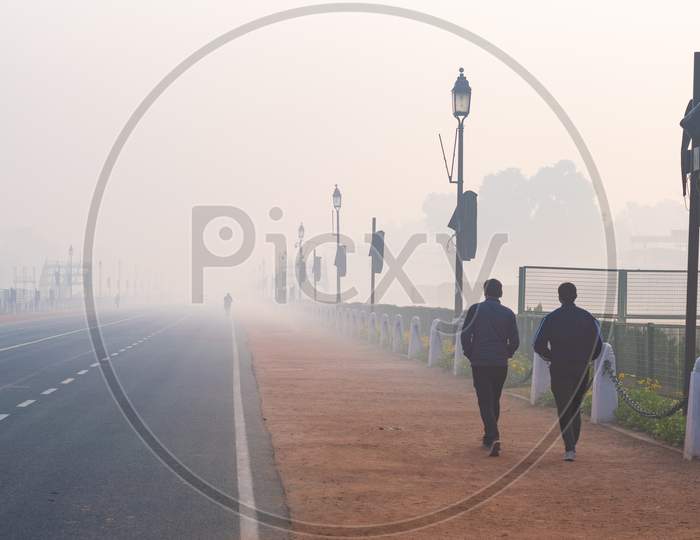Two men walking in the foggy morning during winters in Delhi
