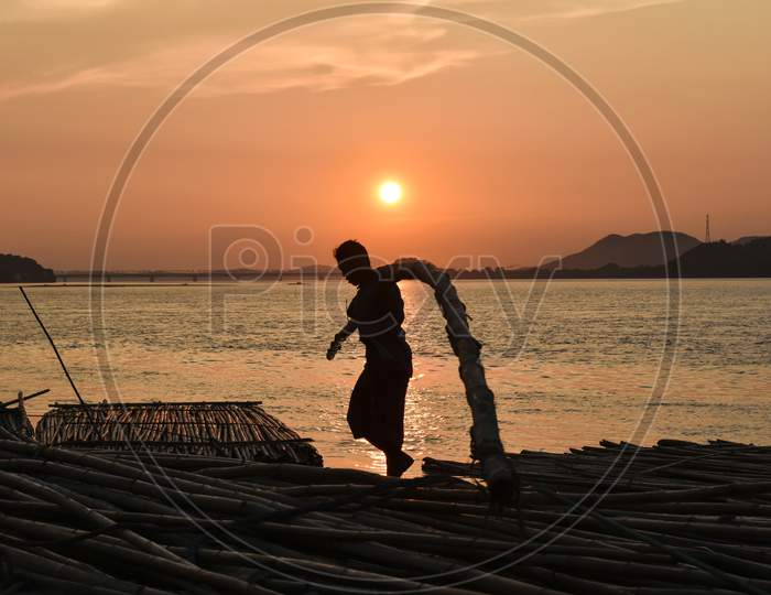 Labourer Carries Bamboo At A Bamboo Market Along With River Brahmaputra In Guwahati, Assam, India