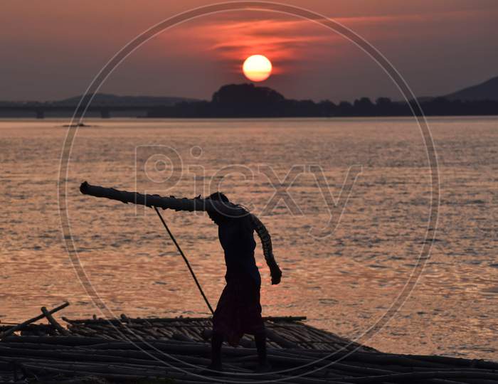 Labourer Carries Bamboo At A Bamboo Market Along With River Brahmaputra In Guwahati, Assam, India