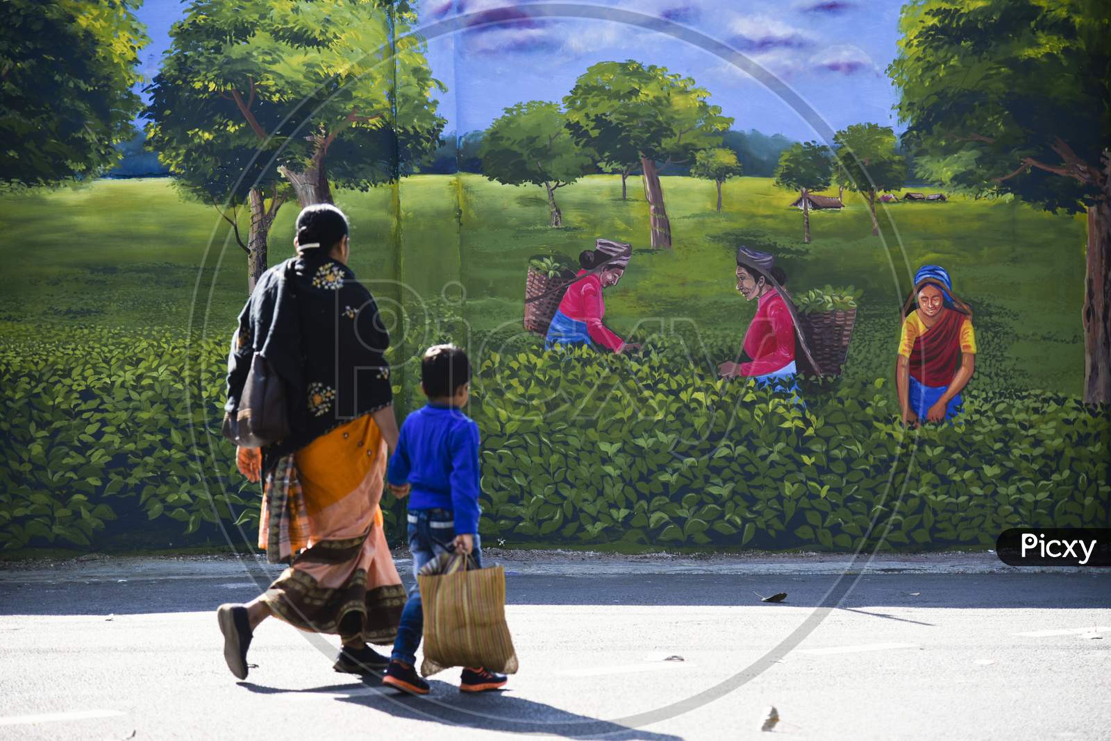 People Walking In Front Of A Mural
