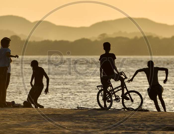 Children Playing In The Banks Of The Brahmaputra River At Sunset, In Guwahati, Assam, India