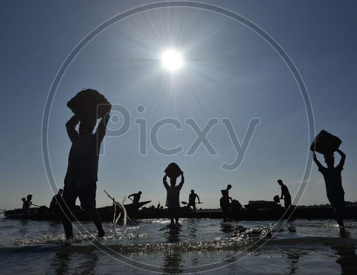 Silhouette of  Labourers Extract Sand From The Riverbed Of The Beki River In Barpeta District Of Assam In India