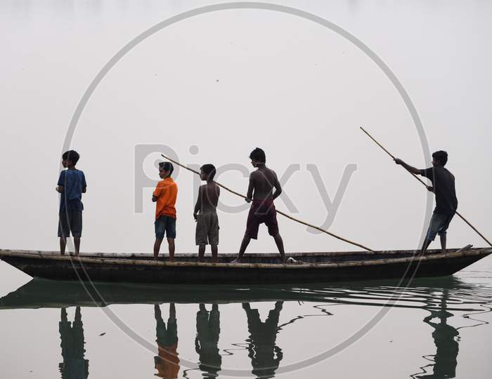 Children Paddle A Boat In A Foggy Evening In Beki River, In Barpeta District Of Assam
