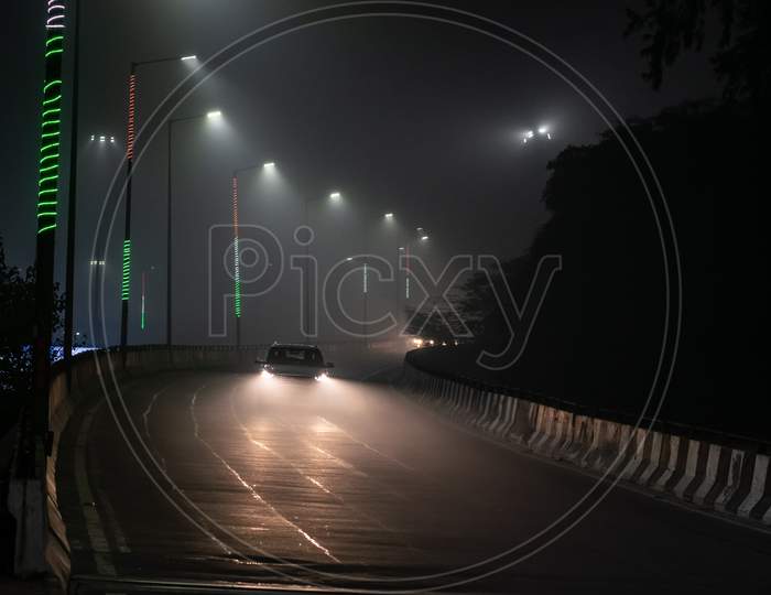 A car passing over flyover during one foggy night during winters in Delhi NCR