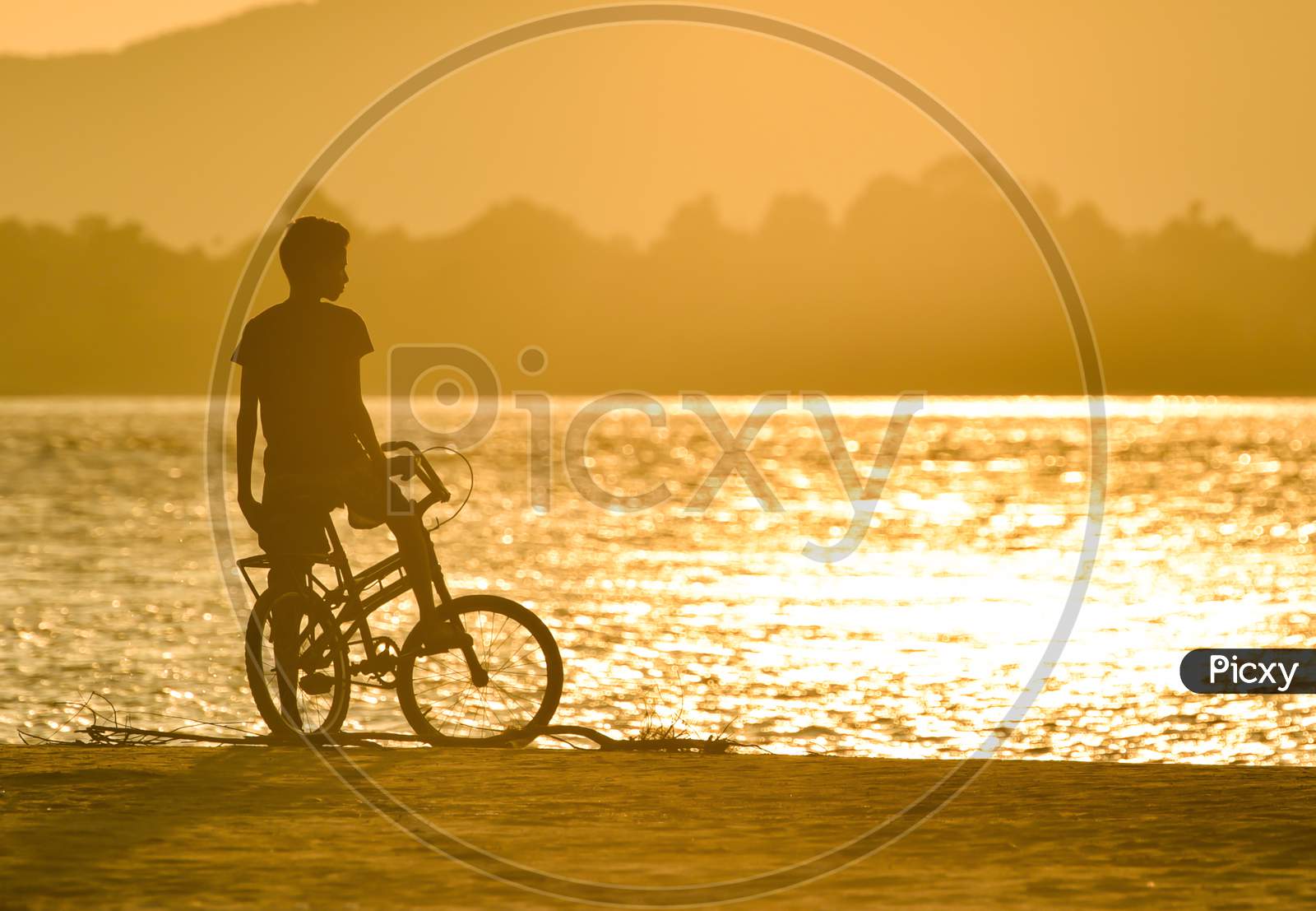 Silhouette of A Boy On Bicycle At Bramhaputra River Bank