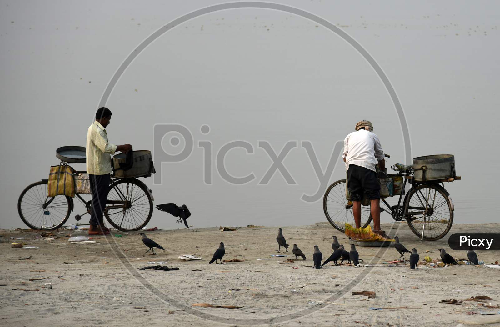Fish Vendor Cleans His Bicycle And Basket After Selling His Catch On The Banks Of The River Brahmaputra In Guwahati