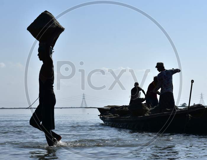 Silhouette of  Labourers Extract Sand From The Riverbed Of The Beki River In Barpeta District Of Assam In India
