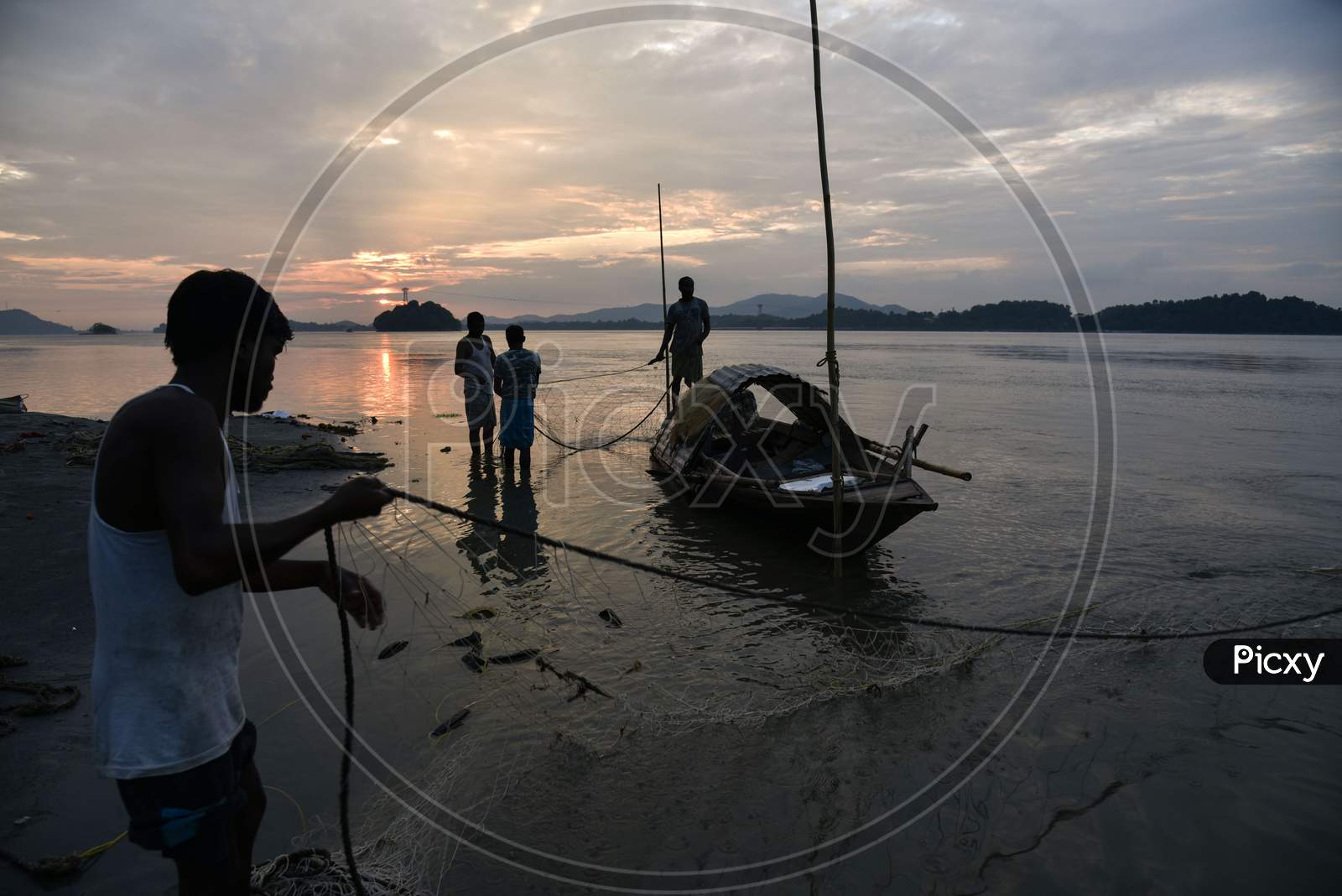Fishermen Cleaning Their Fishing Nets After Fish In The Brahmaputra River, In Guwahati, Assam