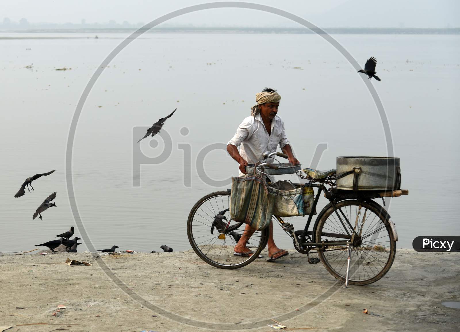 Image of Fish Vendor Cleans His Bicycle And Basket After Selling His Catch  On The Banks Of The River Brahmaputra In Guwahati-DG535072-Picxy