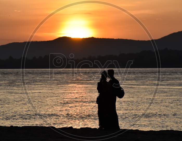 A Couple Takes Selfie During Sunset In The Banks Of The Brahmaputra River, In Guwahati, Assam, India