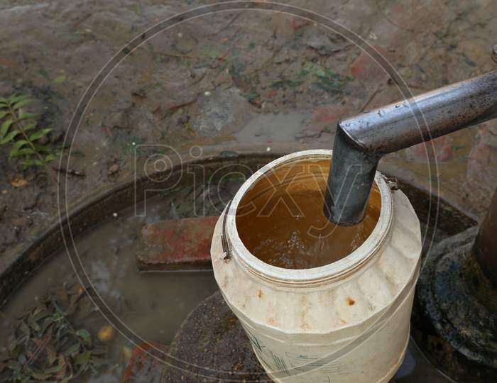 Vessel Filling With Water At a Hand Pump