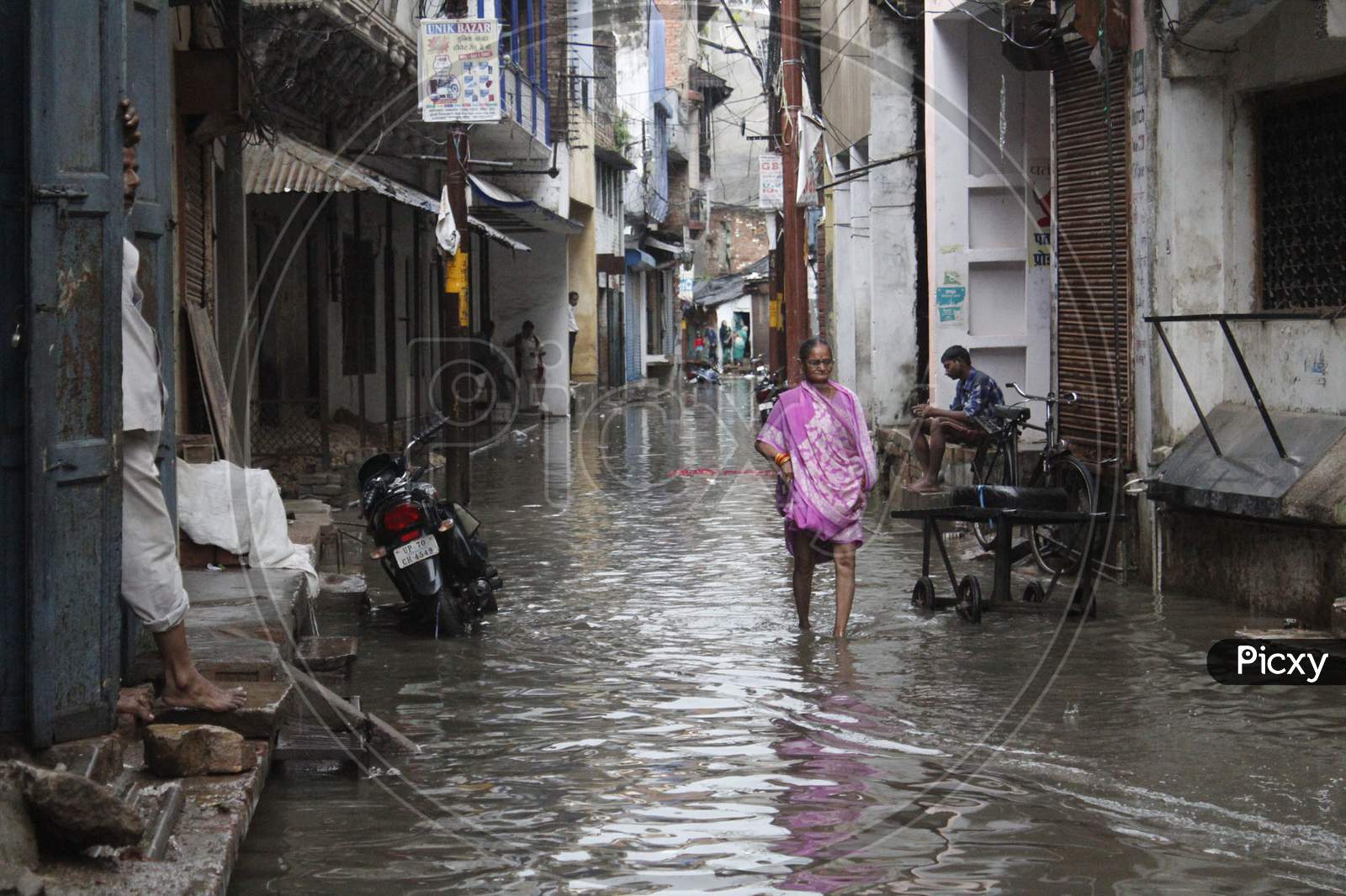 A Woman Cross Rain Water Logged On The Road During Heavy Rain In Prayagraj
