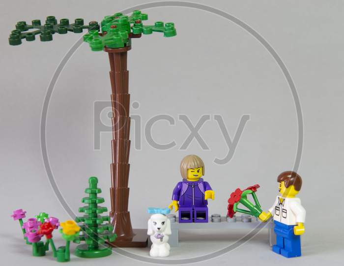 Florianopolis, Brazil. September 19, 2020: Minifigure Of Boy Giving A Bouquet Of Flowers To His Girlfriend In A Forest Garden On White Background. Valentine'S Day. Selective Focus. Copy Space.