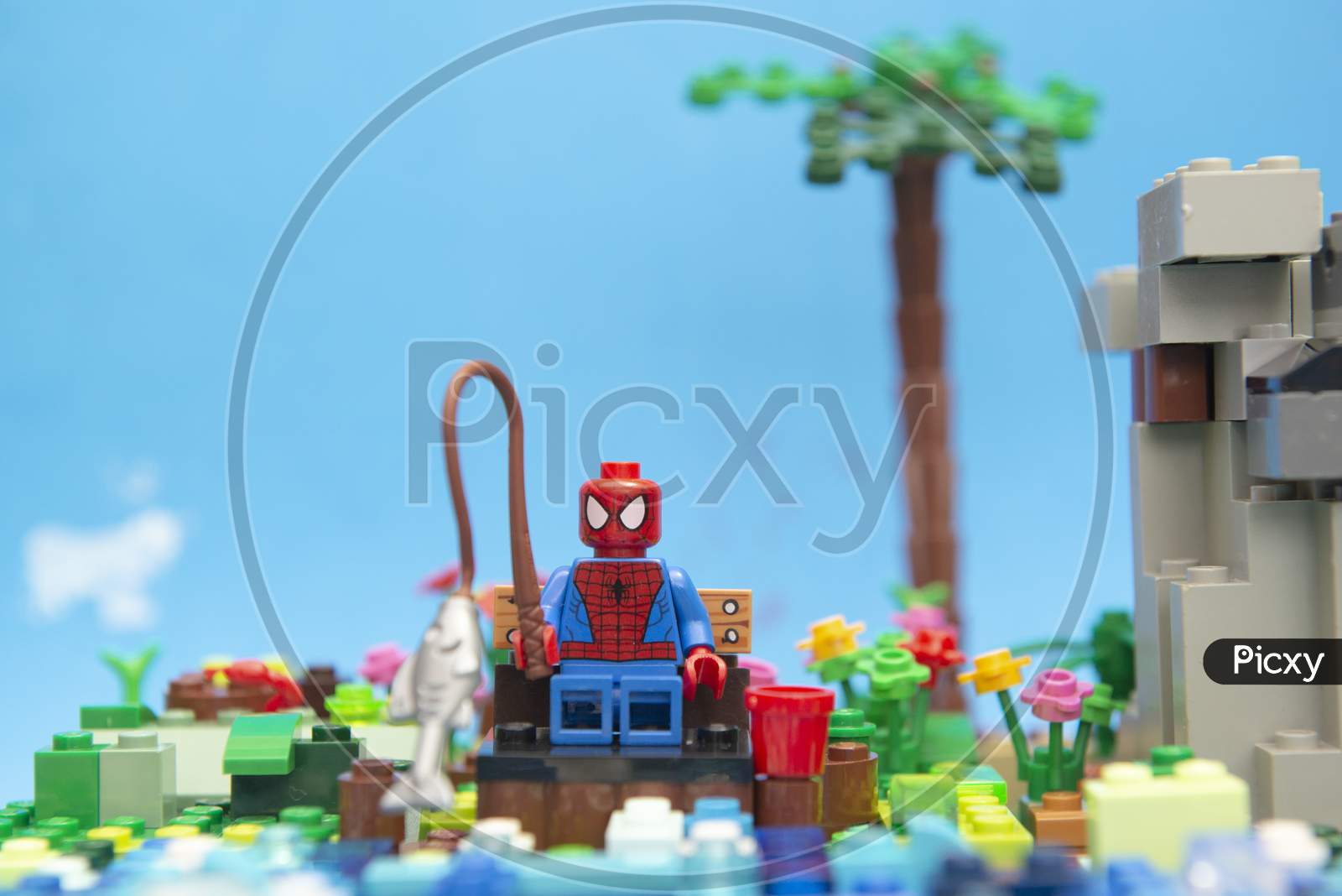 Florianopolis, Brazil. September 20, 2020: Spider Man Minifigure Sitting On A Wooden Bench Enjoying His Vacation And Fishing By The River Next To A Hillside. Concept Of Everyone Deserves Rest.