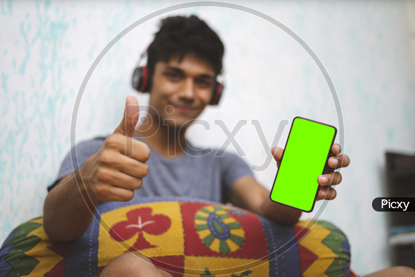 Young Indian Boy Holding A Phone With Green Screen, Showing Thumbs Up In The Background.