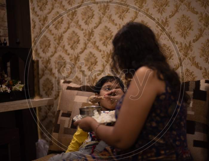 Image Of Bengali Indian Mom Trying To Feed Her Baby Boy Playing With