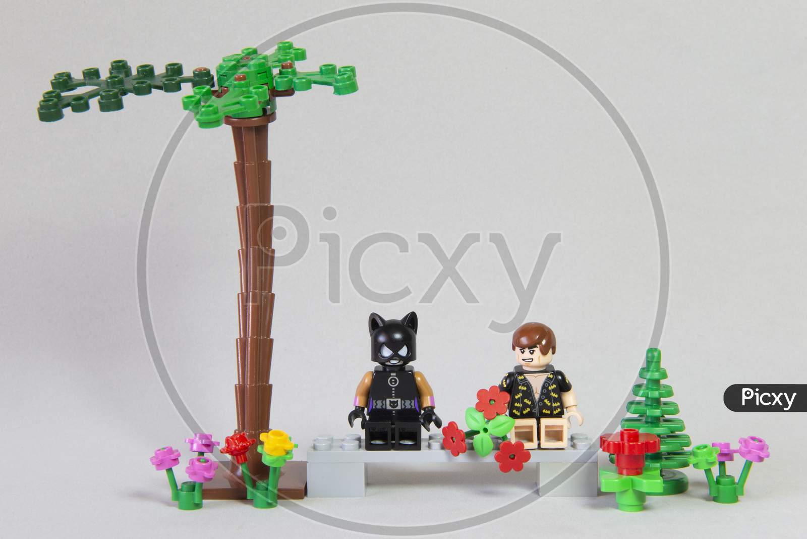 Florianopolis, Brazil. September 19, 2020: Minifigure Of Batman Giving A Bouquet Of Flowers To Cat Woman In A Forest Garden On White Background. Valentine'S Day. Selective Focus. Copy Space.