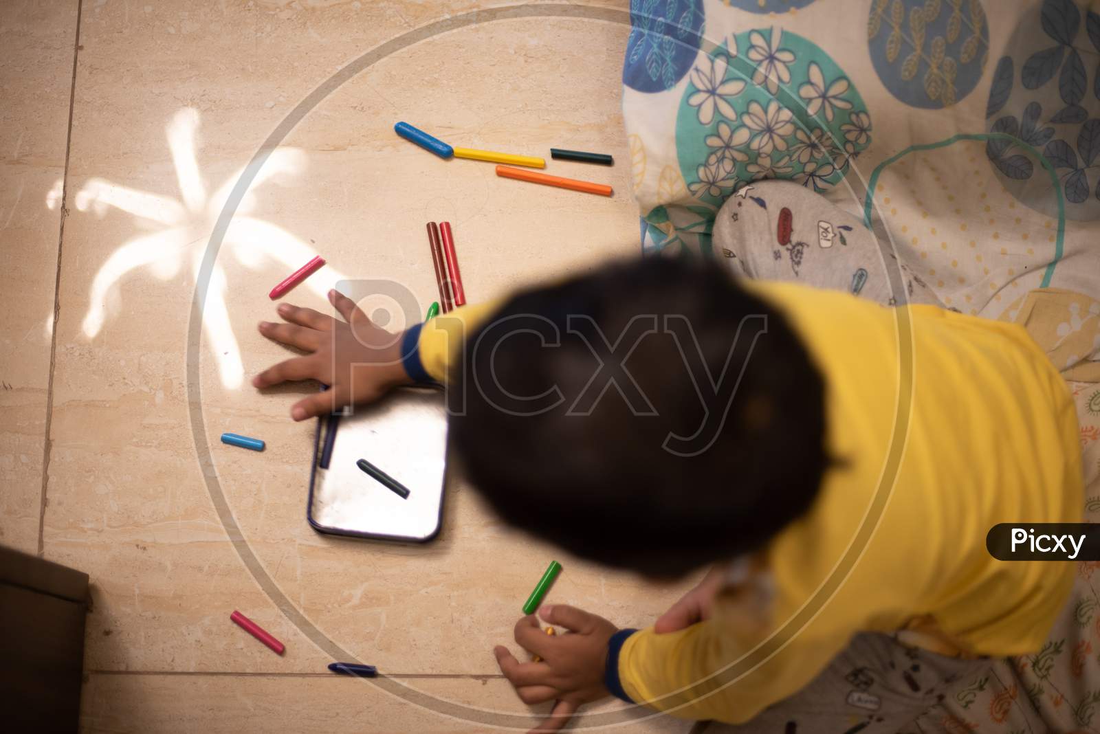 Top view picture of a baby boy playing with color pencils and crayons